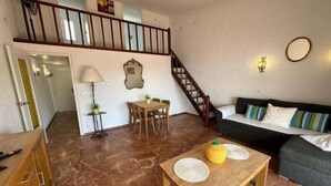 Amplia sala de estar con una mesa de comedor de madera, un sofá y una escalera que conduce a un piso superior.