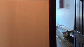 A room with a wooden floor, a door, a wall with a sign, and a small table with a basket. - The Pollock Suite is one of our four rooms. (Hermann)