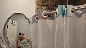 A bathroom with a sink, mirror, and shower curtain. - The Pollock Suite is one of our four rooms. (Hermann)
