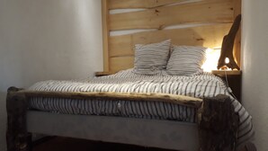 A bed with a wooden headboard, striped bedding, and a bedside table with a lamp. - Appartement Seignosse Océan (seignosse)