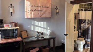A kitchen with a microwave, coffee maker, and a decorative sign on the wall.