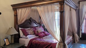 A four-poster bed with a canopy, a bedside table with a lamp, and a framed picture on the nightstand.