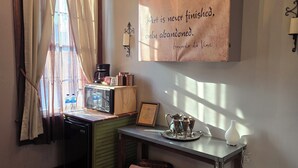 A cozy room with a wooden desk, a chandelier, a framed quote on the wall, and a window with curtains.
