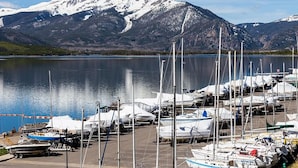 A marina with boats docked, a calm lake, and snow-capped mountains in the background. - Lookout Ridge Townhomes #113 by Summit County Mountain Retreats (Dillon)
