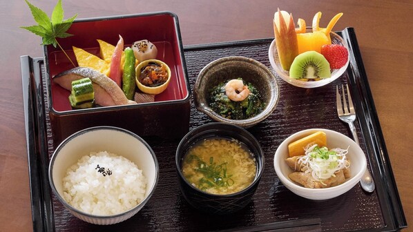Eine traditionelle japanische Bento-Box-Mahlzeit mit Reis, Suppe und verschiedenen Beilagen, darunter Gemüse und Fisch.