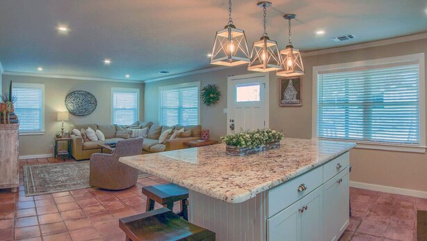 A spacious living room with a large island, a dining area, and a kitchen with a granite countertop.