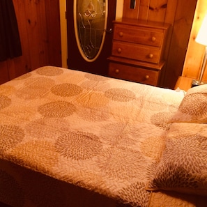 Relax in a serene bedroom with a large bed and a dresser, featuring a round mirror above.