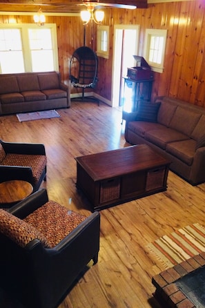 Relax in this inviting living space with a sofa, armchair, and unique hanging chair, perfect for unwinding and reading.
