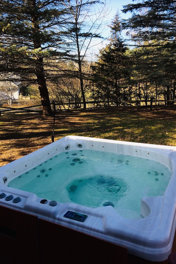 Relax in a hot tub surrounded by lush greenery and a serene atmosphere.