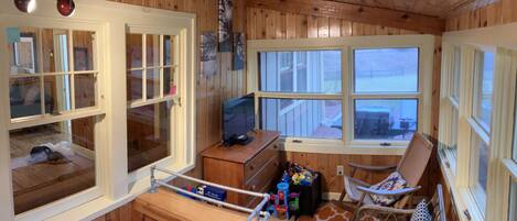 A cabin with wooden walls, a TV, a desk, and two chairs.