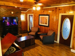 Cozy living room with a fireplace, comfortable seating, and a large window featuring a stained glass design.