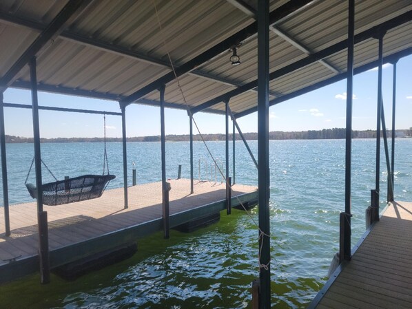 Un muelle cubierto con una silla mecedora, una terraza de madera y vista al agua.