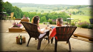 Two people seated at an outdoor table with a scenic view of a green landscape.