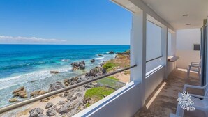 A balcony with a view of the ocean and rocky shoreline. - Casa Perla Suite 2 : Caribbean Oceanfront 2 Bdrm w/rooftop dipping pool (Mid Island)
