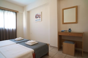 Habitación de hotel con dos camas, un escritorio, una silla, un espejo y un cuadro en la pared.