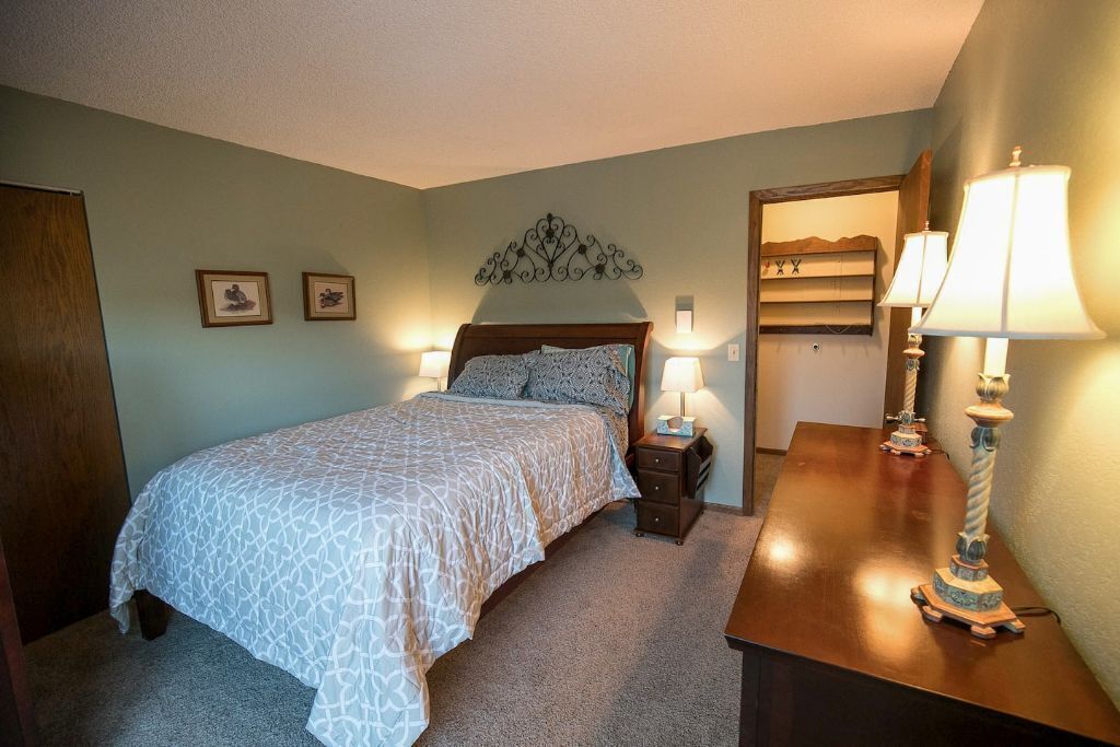 A neatly arranged bedroom with a bed, bedside lamps, and a dresser.