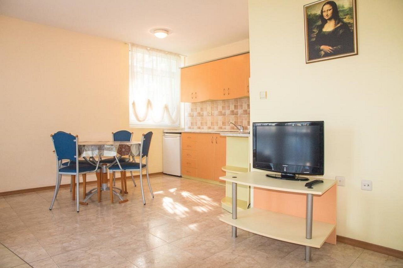 A compact living space with a dining area, kitchenette, and a television.