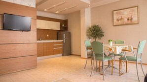 A modern kitchen with wooden cabinets, a built-in refrigerator, and a dining area with a table and chairs. - Elite Apartments Complex II III IV (Sunny Beach)