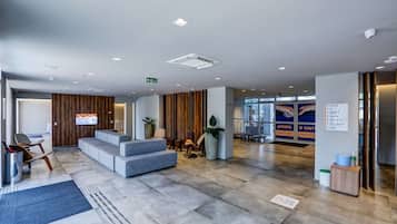 Um lobby moderno com área de estar, balcão de recepção e tela de informação digital.