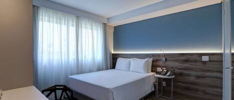 Una habitación de hotel moderna con una cama grande, una mesita de noche con teléfono y una pared de acento de madera.