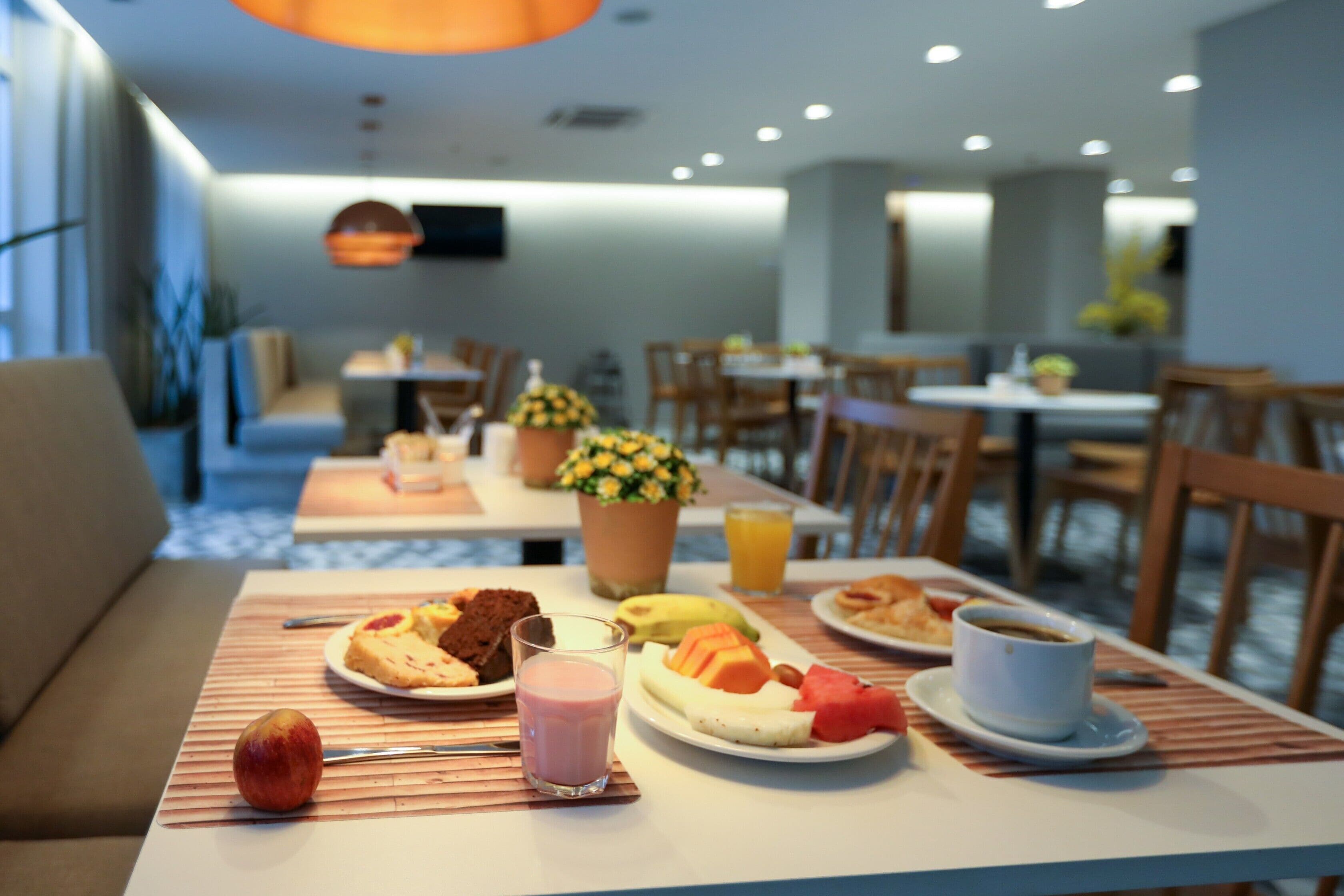 A dining area with tables set for breakfast, including plates of food, a glass of milk, and a cup of coffee.