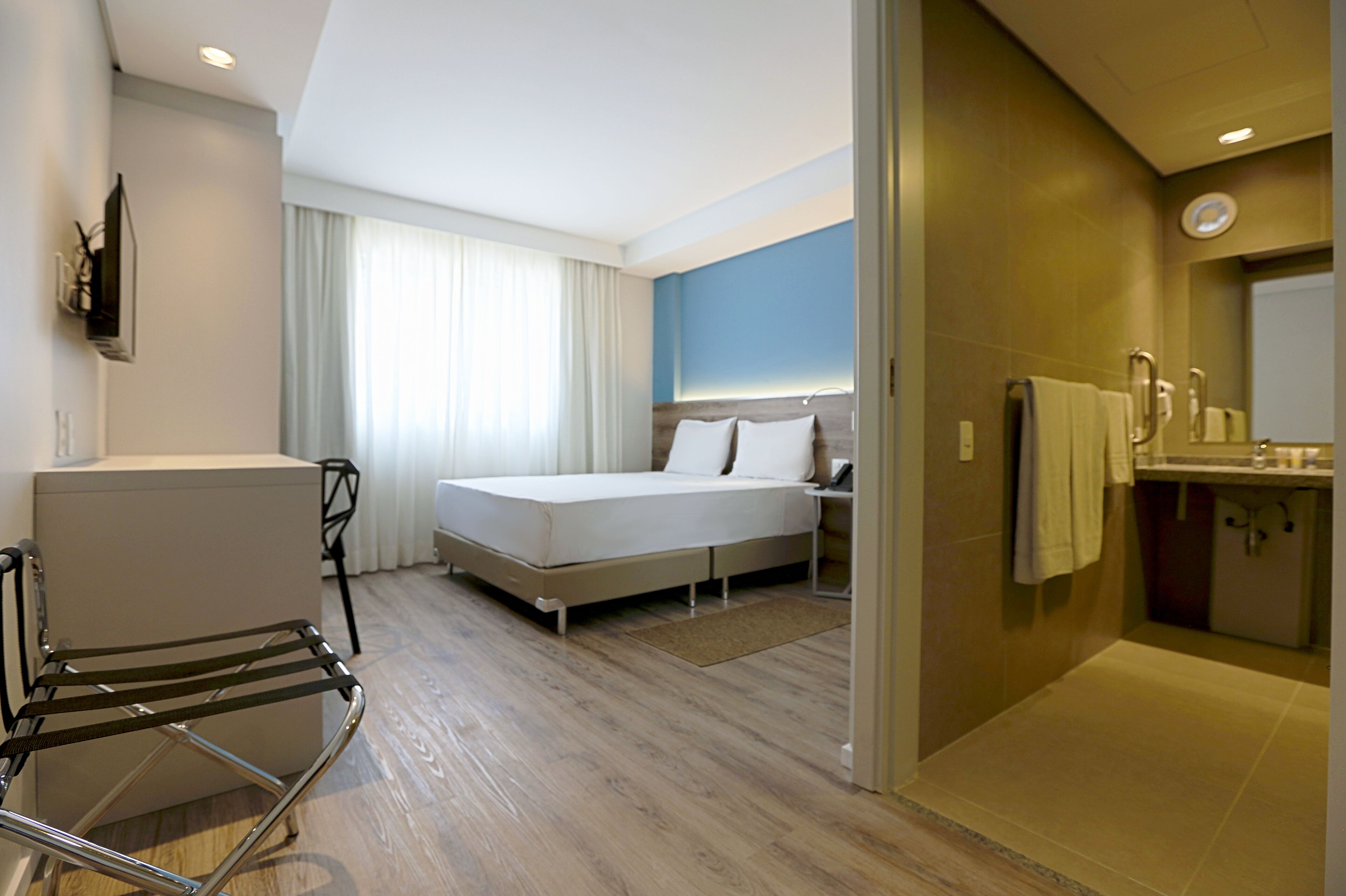 Une chambre d’hôtel équipée d’un lit, d’un bureau, d’une chaise, d’une salle de bain et offrant une vue sur l’extérieur.