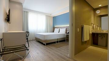 Une chambre d’hôtel équipée d’un lit, d’un bureau, d’une chaise, d’une salle de bain et offrant une vue sur l’extérieur.