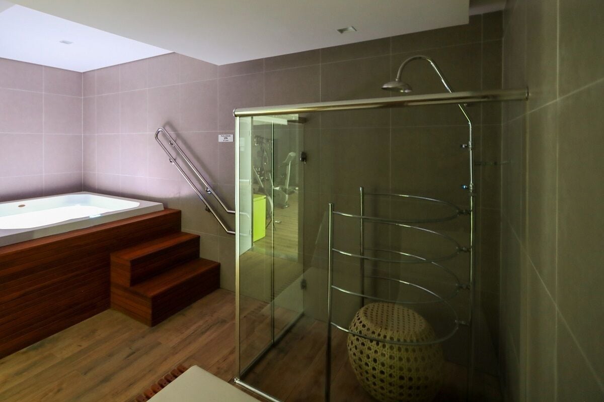 A modern bathroom with a glass-enclosed shower, a wooden bench, and a large bathtub.