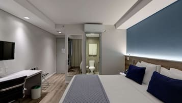 A modern hotel room with a bed, bedside table, and a desk with a chair.