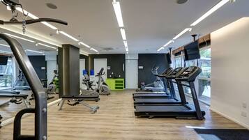 Un gimnasio con cintas de correr, bicicletas estáticas y máquinas de pesas.