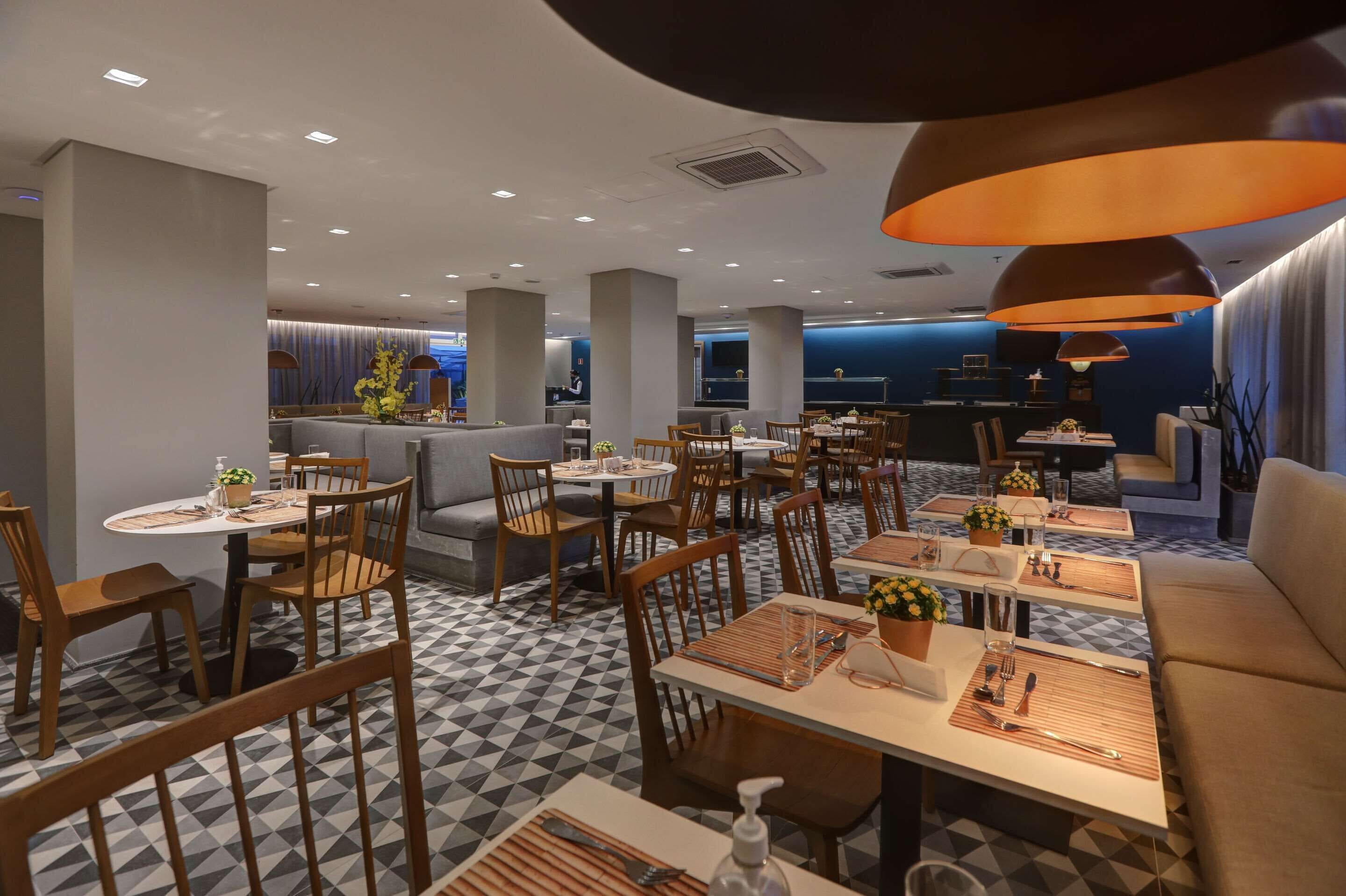 Un restaurant moderne avec un sol à carreaux, des meubles en bois et des luminaires suspendus.