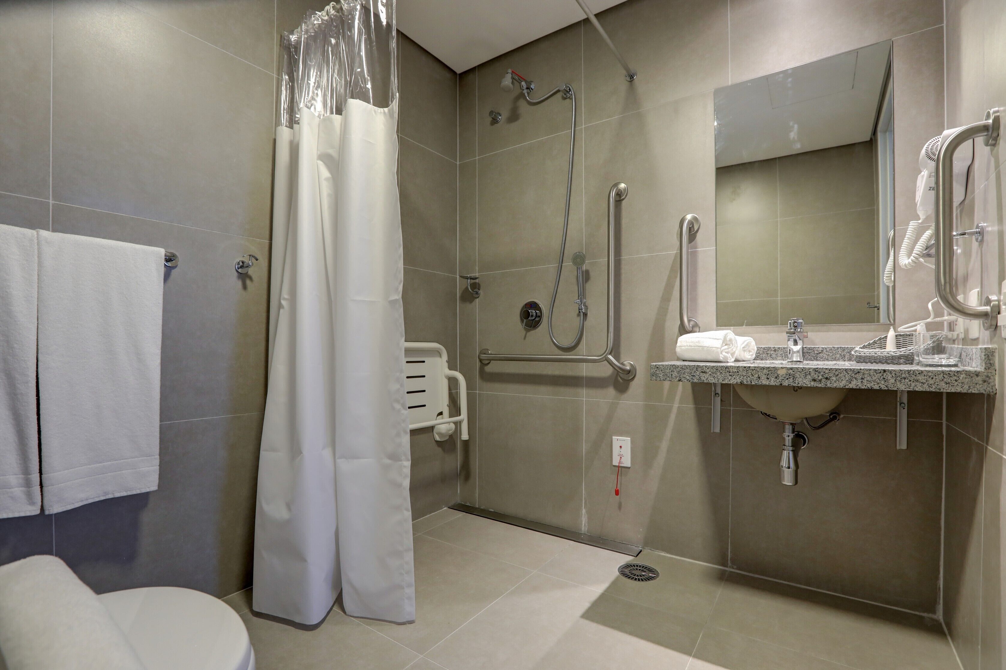 A modern bathroom with a shower, toilet, and sink.