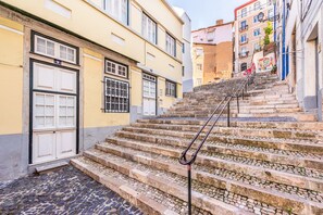 Eine Treppe aus Stein führt zu einem Gebäude mit einer weißen Tür und vergitterten Fenstern.