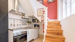 Una cocina moderna con electrodomésticos de acero inoxidable, una escalera de madera y una pared de acento roja.