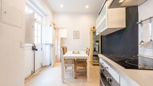 Cocina moderna con comedor, armarios blancos y placa de cocina negra.