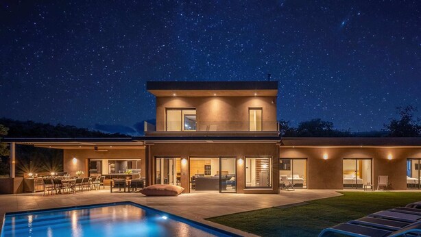 Une maison moderne à deux étages, dotée d’une piscine, d’un espace extérieur aménagé et offrant une vue sur un ciel étoilé.