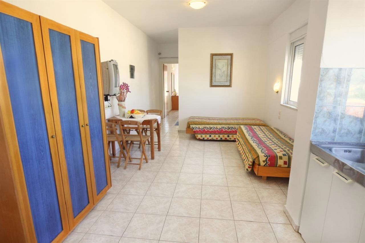 Une pièce de taille modeste comprenant un lit, une table à manger avec des chaises, un coin cuisine et une armoire.