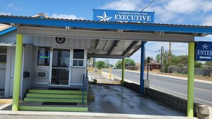 A Carrizo Springs Executive gas station with a blue canopy, a 'Vacancy' sign, and a 'Welcome' sign. - Carrizo Executive Inn (Carrizo Springs)