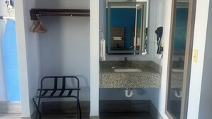 A bathroom with a granite countertop sink, a mirror, and a towel rack. - Carrizo Executive Inn (Carrizo Springs)
