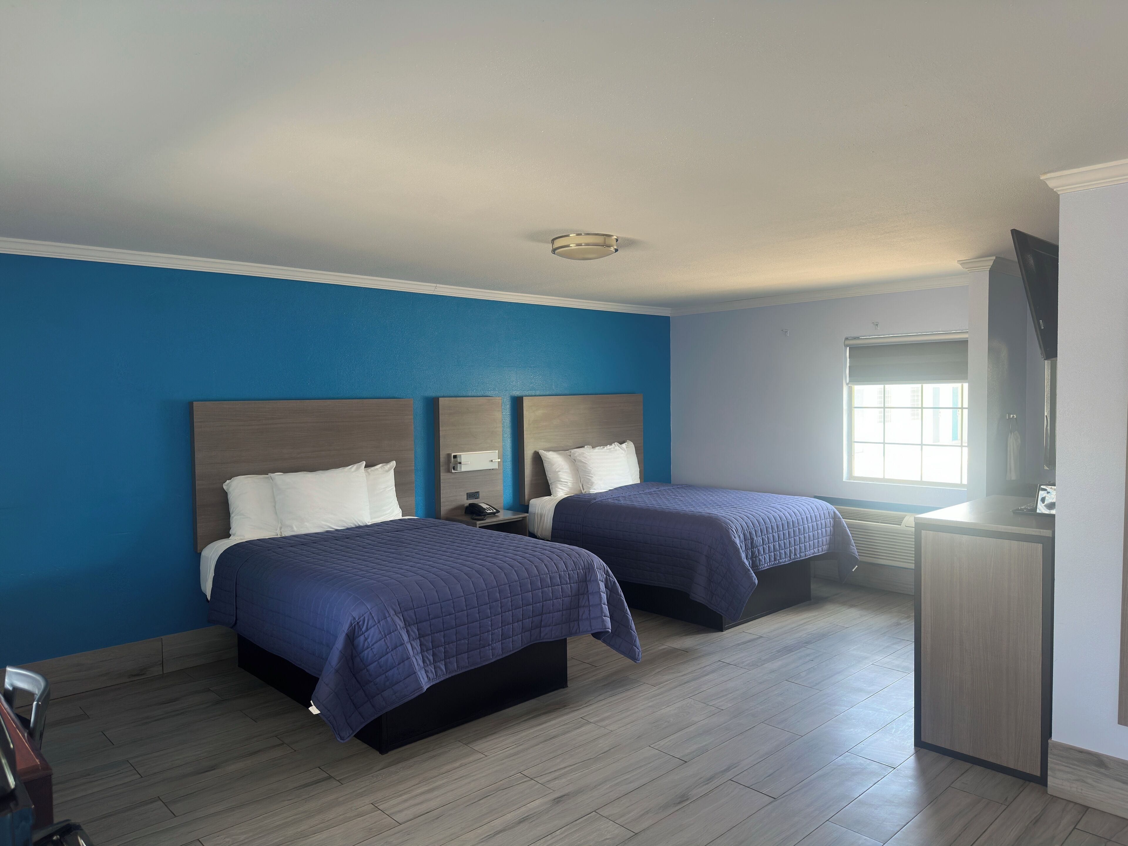 A hotel room with two beds, a desk, and a television.
