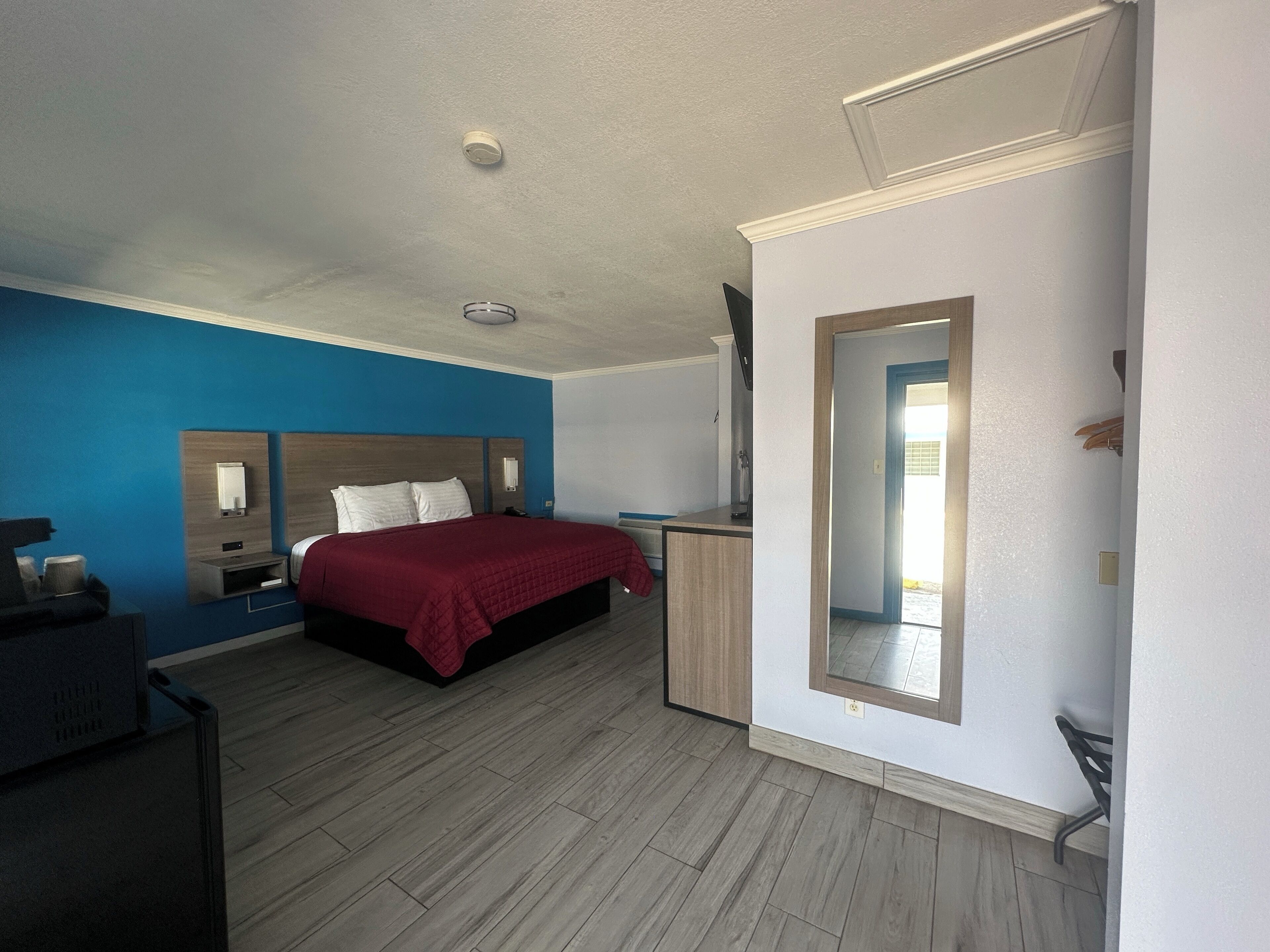 Quarto de hotel moderno com uma cama grande, uma escrivaninha, um espelho e um guarda-roupa.