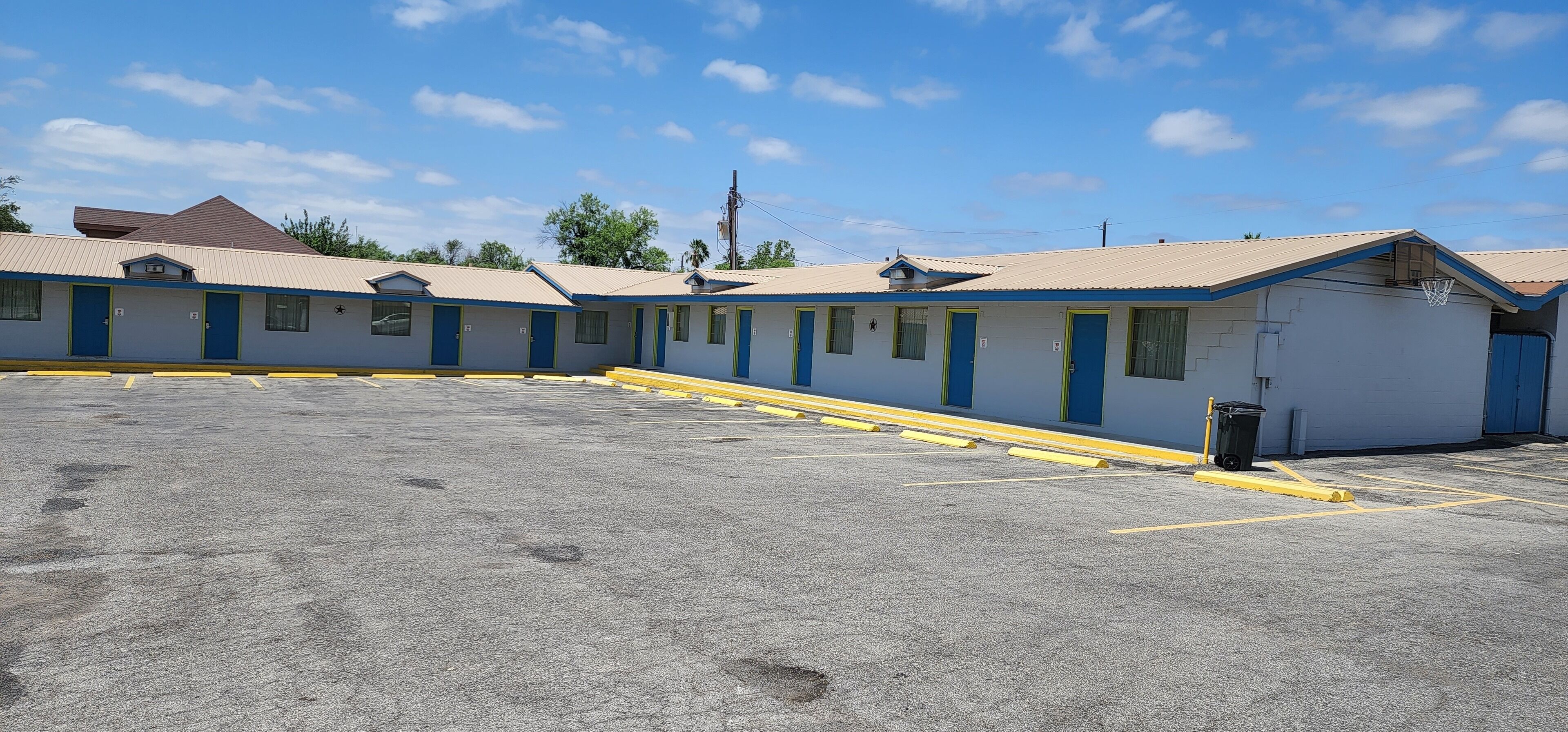Um motel com uma fileira de quartos, estacionamento e uma cesta de basquete.