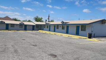 Um motel com uma fileira de quartos, estacionamento e uma cesta de basquete.