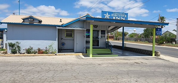 A Carrizo Springs Executive Inn with a blue and white exterior, a covered entrance, and a visible 'Vacancy' sign.