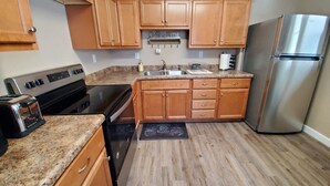 Una cocina con armarios de madera, un refrigerador de acero inoxidable, una estufa y un tostador.