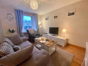 A living room with a sofa, a coffee table, a TV, and a lamp.