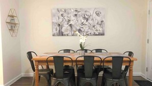 A dining room with a wooden table and six chairs, a floral painting on the wall, and a hexagonal shelf unit. - ★Posh Place ★ King Bed ★ Long Term Stays ★ Duke★ (Durham)