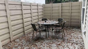 A patio with a round table and four chairs, surrounded by a beige fence and covered with fallen leaves. - ★Posh Place ★ King Bed ★ Long Term Stays ★ Duke★ (Durham)