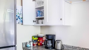Een keuken met een roestvrijstalen koelkast, een koffiezetapparaat en diverse etenswaren op het aanrecht.