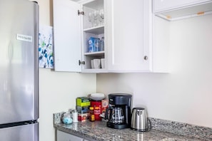 Kitchen features a modern design with a stainless steel refrigerator, granite countertop, and white cabinetry.